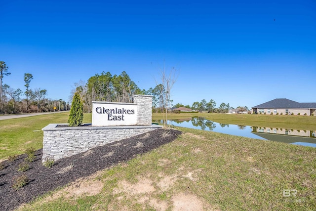 community sign featuring a water view and a lawn