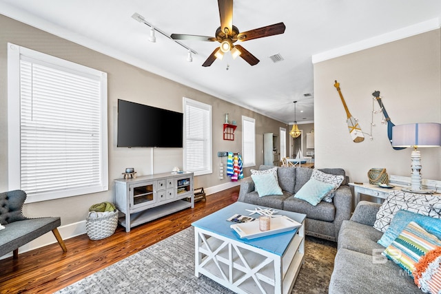 living room featuring ceiling fan, track lighting, dark wood-type flooring, and crown molding