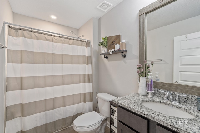 bathroom featuring toilet, vanity, and curtained shower