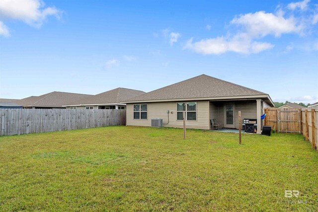 rear view of house with central air condition unit, a lawn, and a patio area