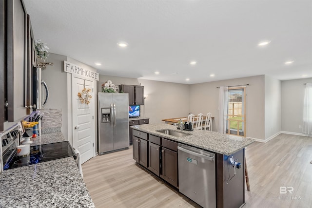 kitchen featuring a kitchen island with sink, sink, light hardwood / wood-style floors, and stainless steel appliances