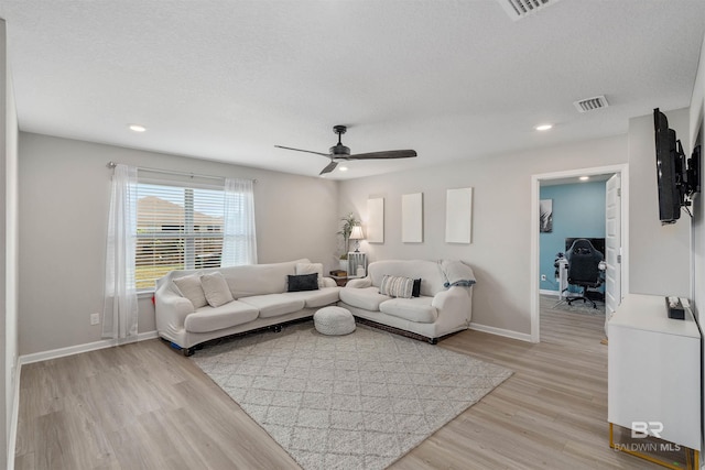 living room featuring a textured ceiling, light hardwood / wood-style flooring, and ceiling fan