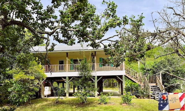 rear view of property featuring a carport, a porch, and a lawn