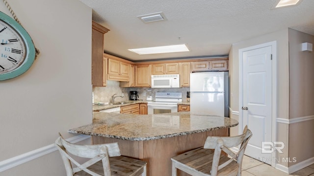 kitchen featuring a breakfast bar, sink, light brown cabinets, kitchen peninsula, and white appliances