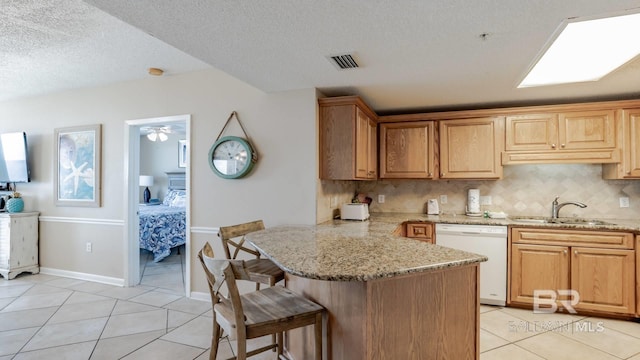 kitchen with dishwasher, sink, backsplash, a kitchen breakfast bar, and kitchen peninsula