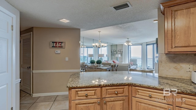 kitchen featuring light tile patterned floors, kitchen peninsula, a textured ceiling, and decorative backsplash