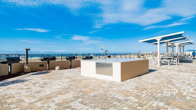 view of patio / terrace featuring a water view, area for grilling, and an outdoor kitchen