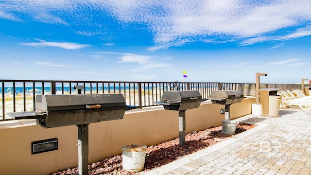 view of patio / terrace with a water view, area for grilling, and a view of the beach