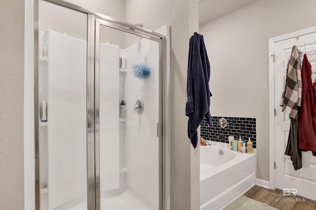 bathroom with independent shower and bath, tasteful backsplash, and hardwood / wood-style flooring