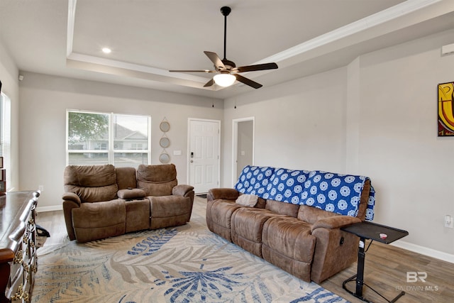 living room featuring wood-type flooring, a raised ceiling, and ceiling fan