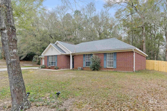 ranch-style house featuring a front yard, fence, brick siding, and roof with shingles