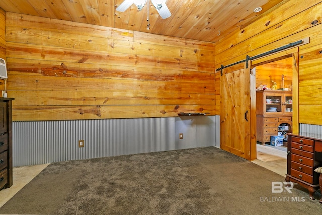 interior space with a barn door, carpet floors, wood ceiling, and wood walls