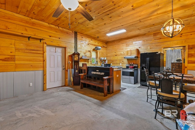 interior space with electric range, black fridge, wood walls, decorative light fixtures, and ceiling fan with notable chandelier