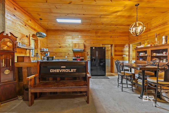 carpeted dining area with a notable chandelier, wooden ceiling, sink, and wooden walls