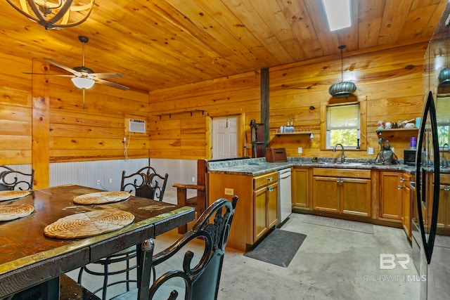 kitchen with pendant lighting, dark stone counters, sink, wooden walls, and ceiling fan