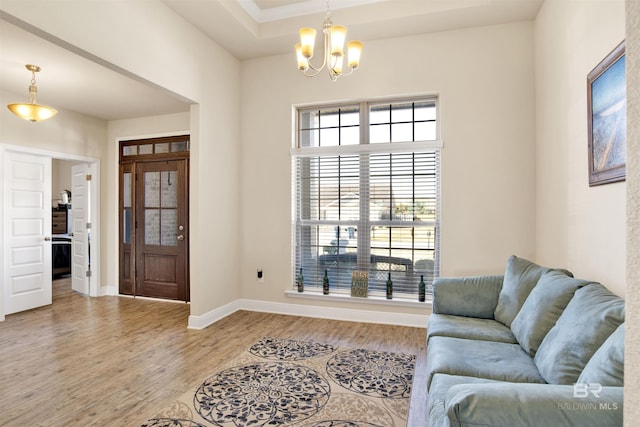 living room featuring light hardwood / wood-style floors, an inviting chandelier, and a tray ceiling