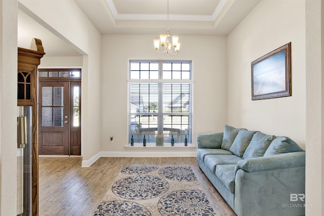 interior space featuring a chandelier, a tray ceiling, light hardwood / wood-style flooring, and crown molding