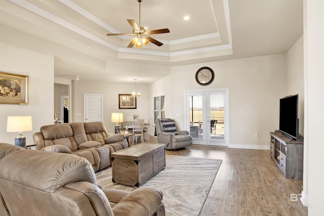 living room with ornamental molding, a tray ceiling, ceiling fan, and light hardwood / wood-style floors