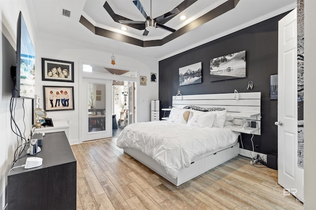 bedroom with ceiling fan, crown molding, light hardwood / wood-style flooring, and a raised ceiling