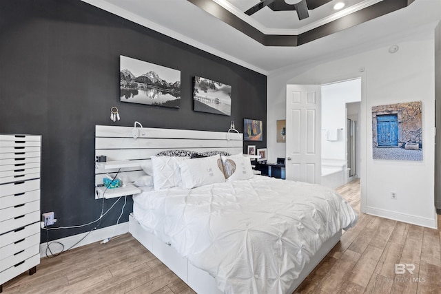 bedroom with ornamental molding, a raised ceiling, ceiling fan, and hardwood / wood-style flooring