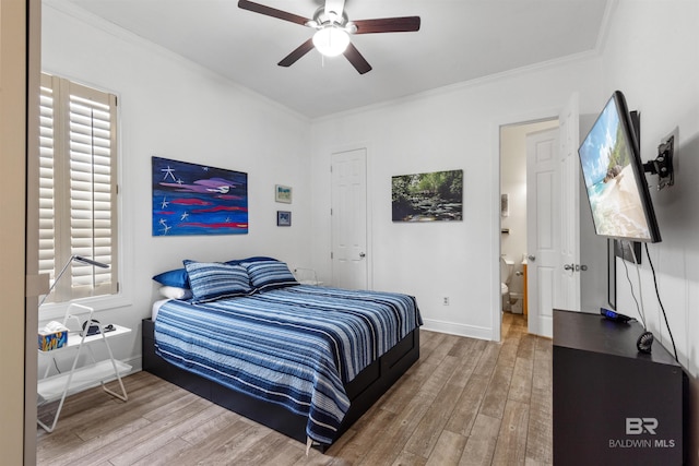 bedroom featuring ceiling fan, hardwood / wood-style floors, ornamental molding, and connected bathroom