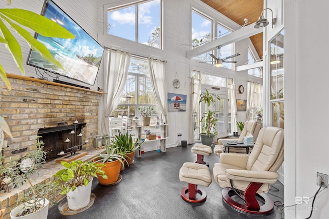 sunroom / solarium with wood ceiling, a fireplace, ceiling fan, and a healthy amount of sunlight