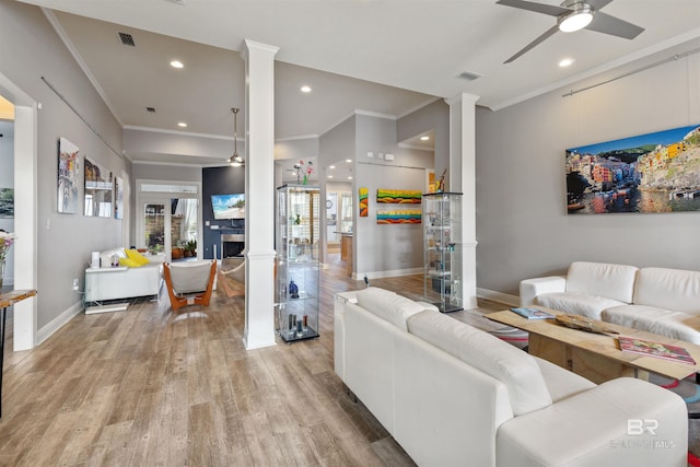 living room with ornate columns, ceiling fan, crown molding, and light wood-type flooring