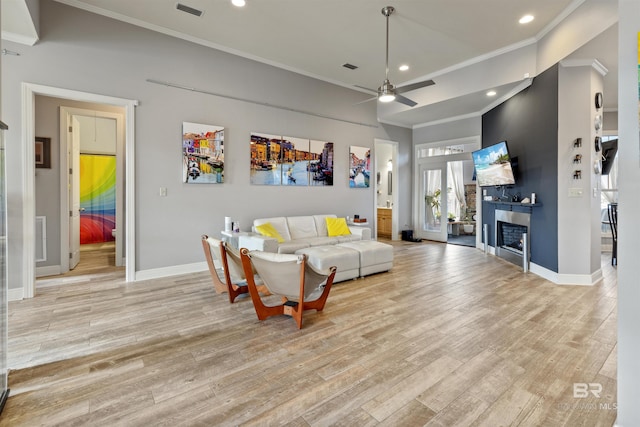 living room featuring light hardwood / wood-style floors, ceiling fan, and crown molding