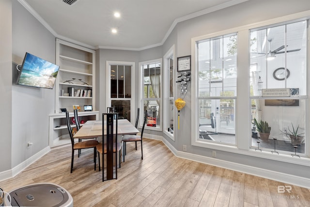 dining room featuring crown molding, built in features, and light hardwood / wood-style flooring