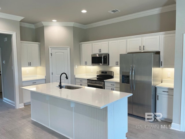 kitchen with appliances with stainless steel finishes, white cabinetry, sink, and a center island with sink