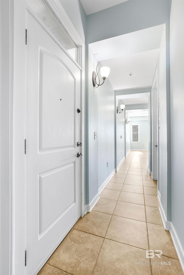 corridor with light tile patterned flooring and baseboards