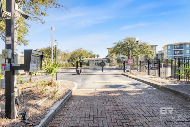 view of road with a gated entry, curbs, street lighting, and a gate