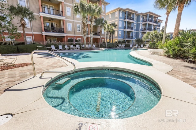 community pool featuring a patio area, a community hot tub, and fence