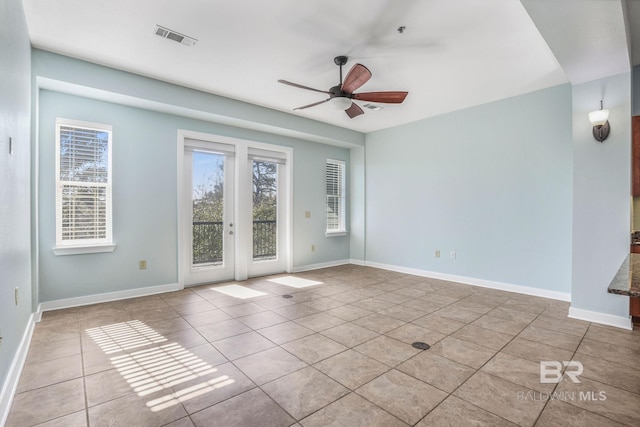 tiled empty room with visible vents, baseboards, and ceiling fan