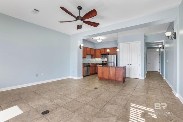 kitchen featuring baseboards, visible vents, a kitchen island, ceiling fan, and appliances with stainless steel finishes