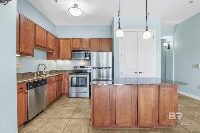 kitchen featuring a center island, dark stone counters, brown cabinetry, stainless steel appliances, and a sink