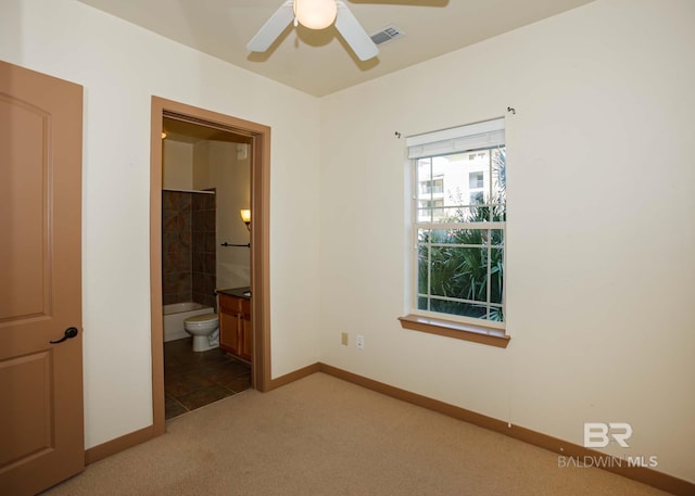 unfurnished bedroom featuring carpet flooring, ensuite bathroom, and ceiling fan