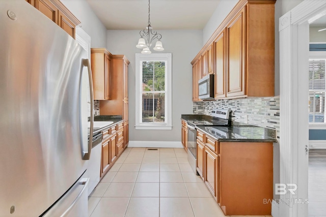 kitchen featuring decorative backsplash, baseboards, light tile patterned floors, a notable chandelier, and stainless steel appliances