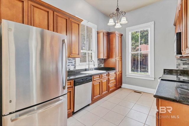 kitchen with brown cabinetry, light tile patterned flooring, tasteful backsplash, a sink, and stainless steel appliances