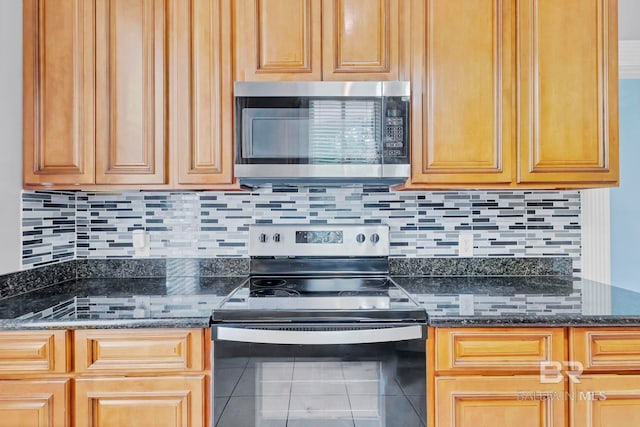 kitchen with dark stone counters, tile patterned floors, appliances with stainless steel finishes, and decorative backsplash