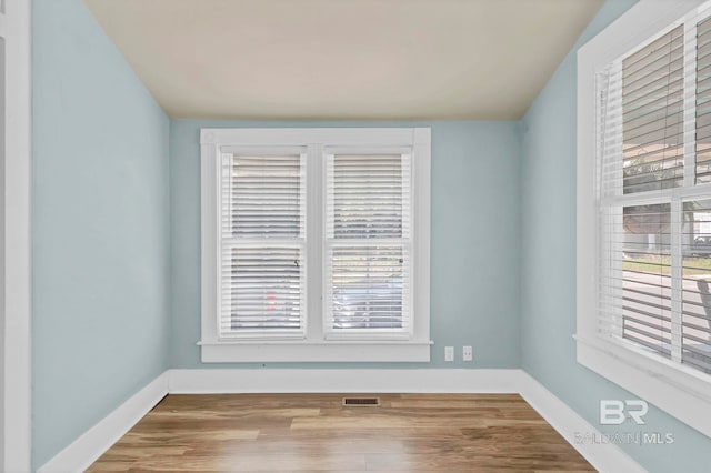 unfurnished room featuring plenty of natural light, wood finished floors, and visible vents