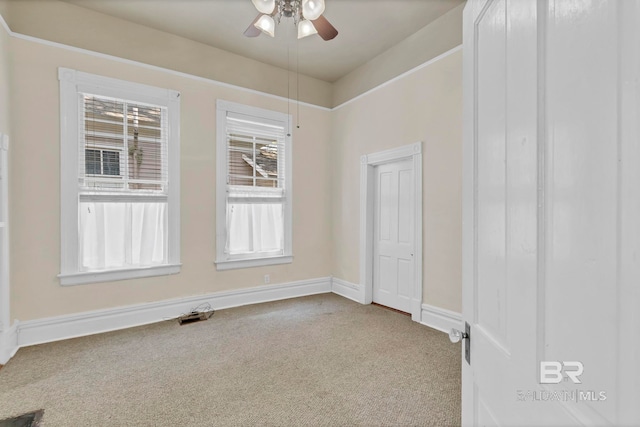 carpeted spare room featuring baseboards and ceiling fan