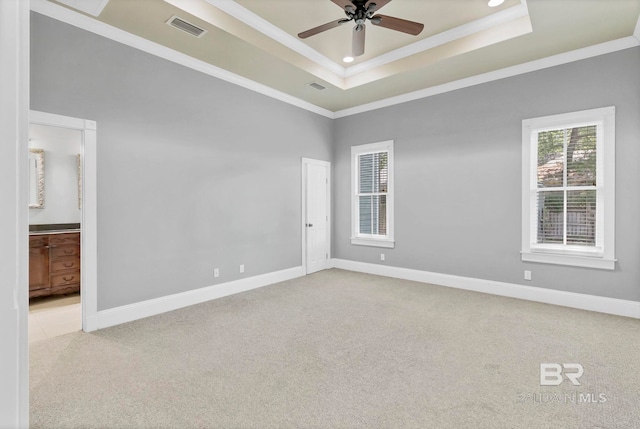 carpeted spare room featuring crown molding, a ceiling fan, a tray ceiling, and visible vents