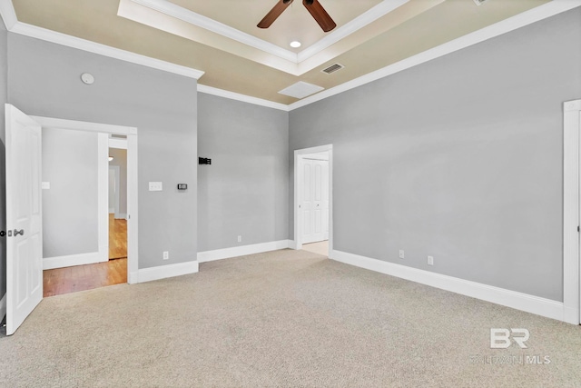 unfurnished bedroom with carpet flooring, baseboards, a tray ceiling, visible vents, and ornamental molding