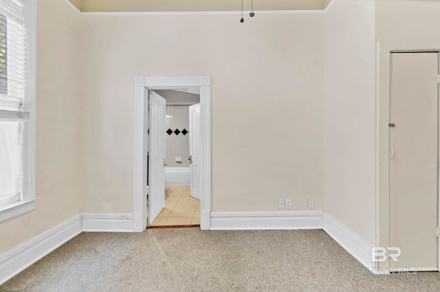 unfurnished bedroom with carpet floors, baseboards, tile patterned floors, and ensuite bath