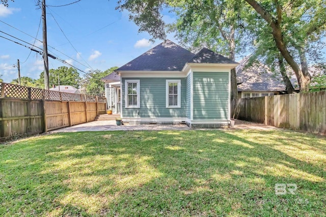 back of house featuring a lawn, a shingled roof, a fenced backyard, and a patio area