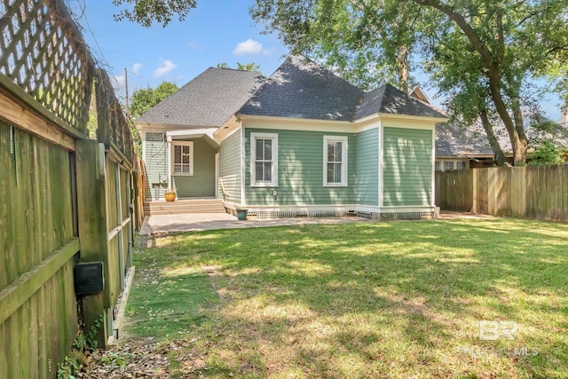 back of property with a yard, a patio, a shingled roof, and a fenced backyard