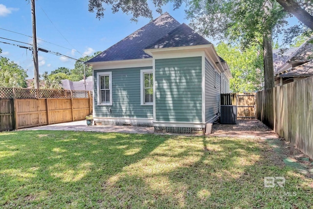 back of house with a fenced backyard, a lawn, and roof with shingles