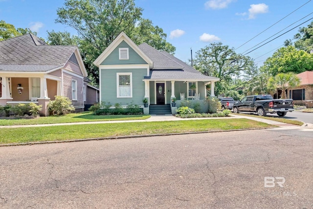 view of front of home with a shingled roof, a porch, and a front yard