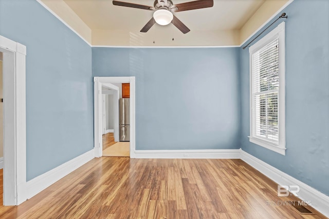 spare room with baseboards, a ceiling fan, light wood-style flooring, and visible vents
